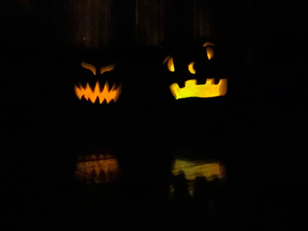 Two glowing jack-o'-lanterns at night
