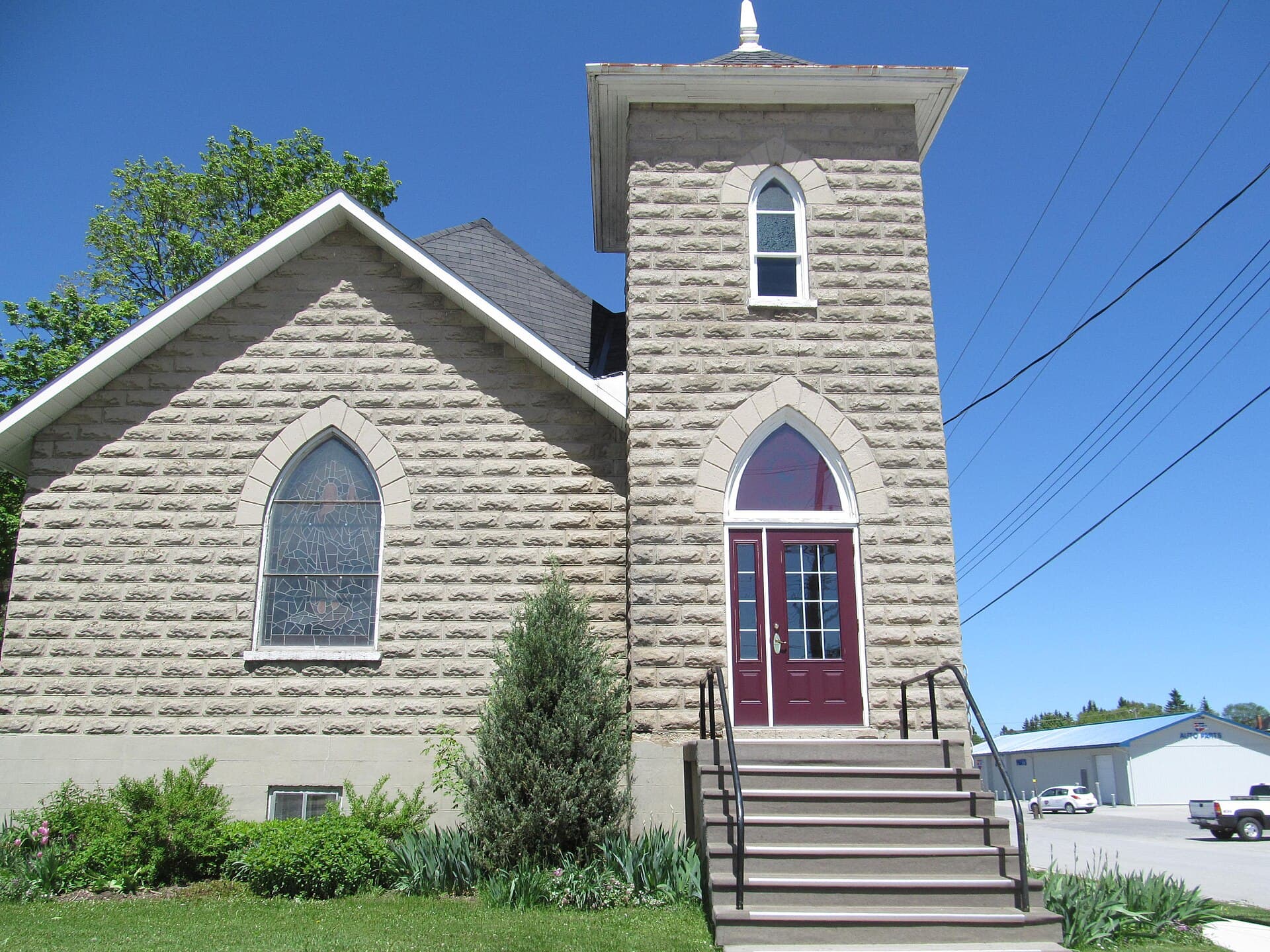 A stone church with a bell tower and red doors in Markdale, Ontario