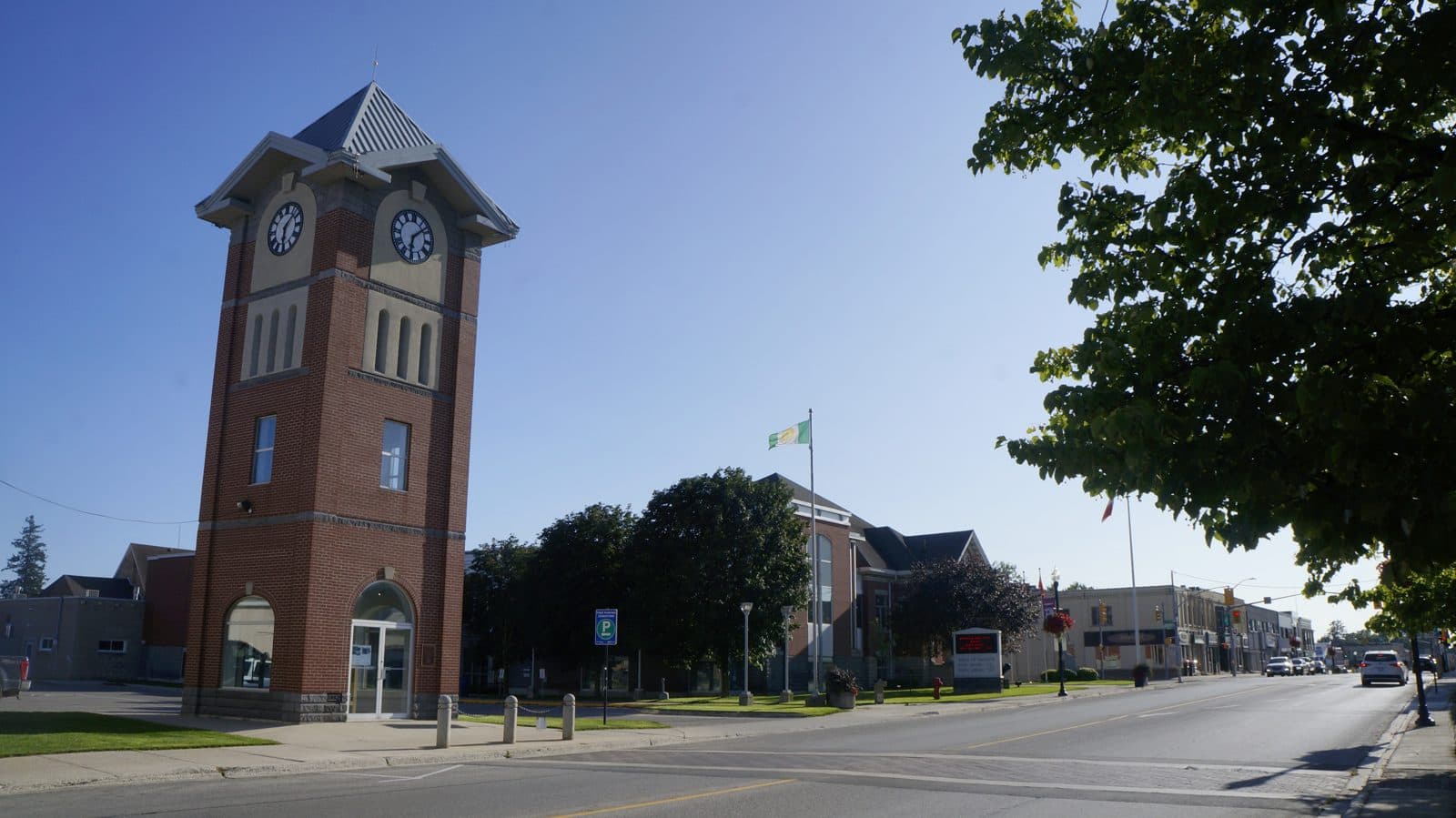 A red-brick clock tower beside a street in downtown Hanover, Ontario, on a sunny day.